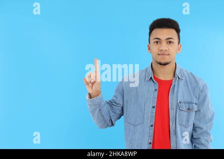 Junger Mann in Jeans-Hemd auf blauem Hintergrund Stockfoto