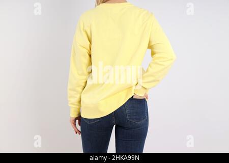 Frau in leerem Sweatshirt auf hellgrauem Hintergrund Stockfoto