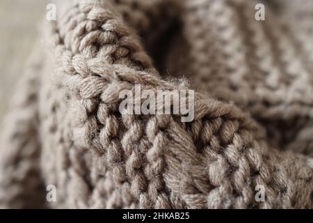 Gestricktes großes handgemachtes Karabinaid aus Acrylgarn, sehr dickes Garn, Modekonzept. Nahaufnahme einer Strickdecke, Hintergrund, selektiver Fokus. Stockfoto