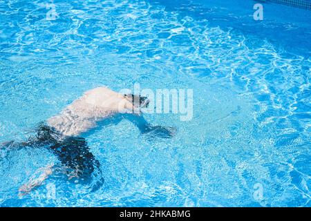 Junger Mann, der den Tag am Schwimmbad ausklingen lassen kann Stockfoto