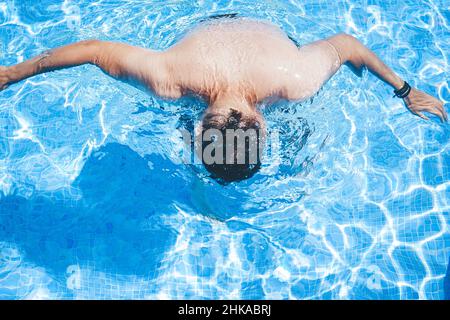 Junger Mann, der den Tag am Schwimmbad ausklingen lassen kann Stockfoto