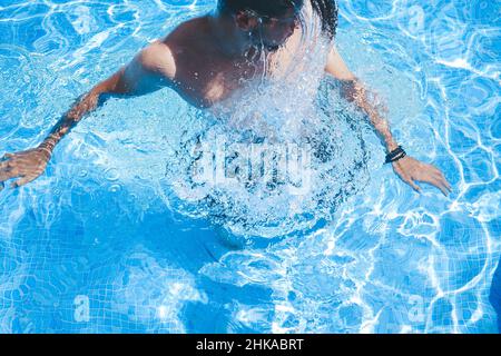Junger Mann, der den Tag am Schwimmbad ausklingen lassen kann Stockfoto