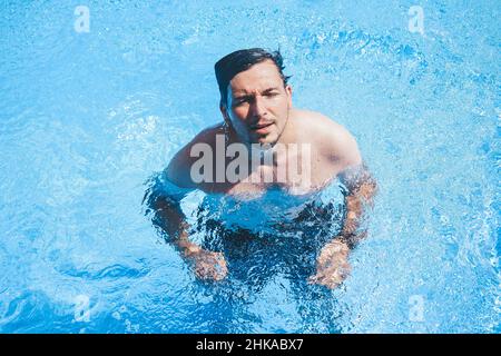 Junger Mann, der den Tag am Schwimmbad ausklingen lassen kann Stockfoto