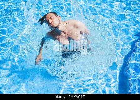 Junger Mann, der den Tag am Schwimmbad ausklingen lassen kann Stockfoto