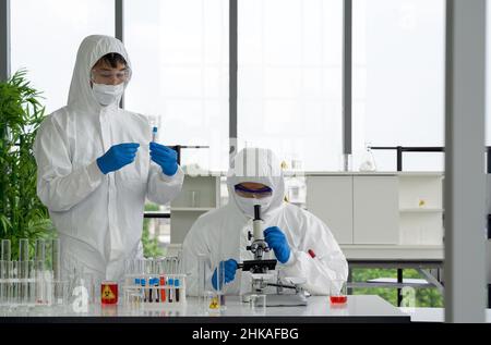 Epidemiologische Forscher in Virusschutzkleidung untersuchen Blutproben von Patienten, die mit Covid-19 infiziert sind. Omicron Dehnungsmessung Stockfoto