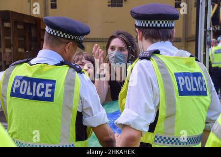 Polizeibeamte sprechen mit einem Demonstranten, der sich während eines Protestes zur Ausrottung der Rebellion im Cambridge Circus an einen Transporter befestigte, der die Straßen blockierte. London, Großbritannien 24th. August 2021. Stockfoto