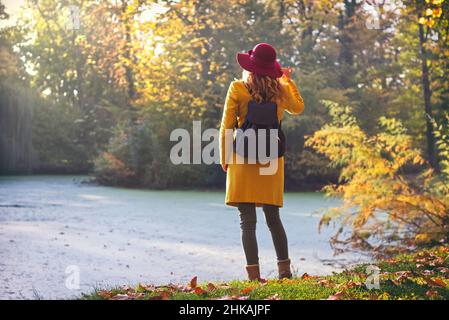 Tourist Mädchen mit Rucksack genießt indischen Sommer im öffentlichen Park. Fröhlicher Reisender in der Herbstsaison Stockfoto
