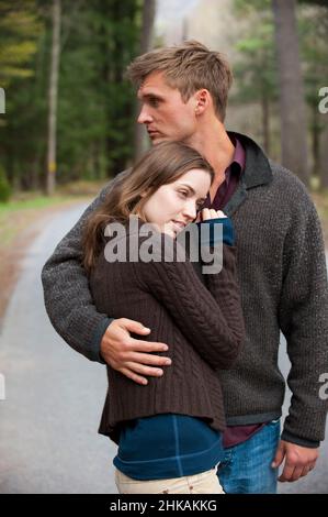 Junger Mann mit Arm um junge Frau Stockfoto
