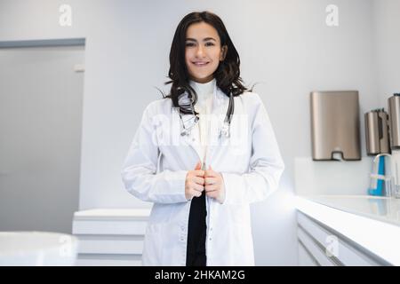 Porträt einer schönen glücklichen Ärztin, die im Krankenhausbüro steht Stockfoto