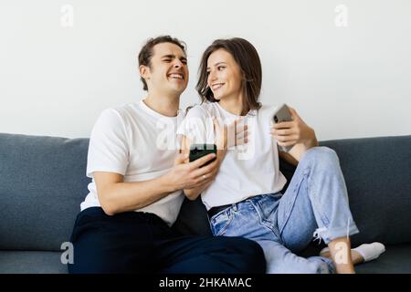 Mobile Suchtkonzept, junges Paar mit Smartphones auf dem Sofa entspannen, Millennial Mann und Frau besessen von neuen Apps oder sozialen Netzwerken, Telefon A Stockfoto