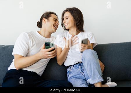 Mobile Suchtkonzept, junges Paar mit Smartphones auf dem Sofa entspannen, Millennial Mann und Frau besessen von neuen Apps oder sozialen Netzwerken, Telefon A Stockfoto