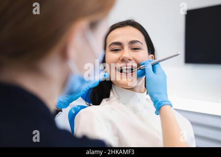 Hübsche Brünette Frau beim Zahnarzttermin. Weibliche Patientin behandelt ihre Zähne in einer Zahnklinik Stockfoto