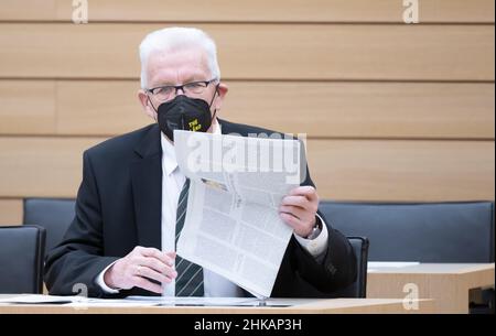 Stuttgart, Deutschland. 03rd. Februar 2022. Winfried Kretschmann (Bündnis 90/die Grünen), Ministerpräsident von Baden-Württemberg, legt vor Beginn einer Plenardebatte eine Zeitung auf seinen Sitz auf der Regierungsbank. Quelle: Bernd Weißbrod/dpa/Alamy Live News Stockfoto