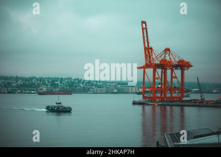 Seabus kommt im Hafen an mit rotem Kranschiffhafen im Hintergrund mit Frachtschiff im Rücken Stockfoto