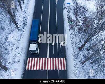 LKW auf der Straße in Bewegung. Fußgängerüberweg mit erhöhter Gefahr der roten Farbe Stockfoto