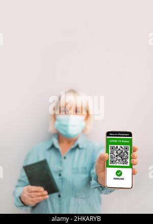 Geimpfte Person mit Mobiltelefon und digitalem Gesundheitspass für Reisen während der Covid-19-Pandemie. Grünes Zertifikat Stockfoto