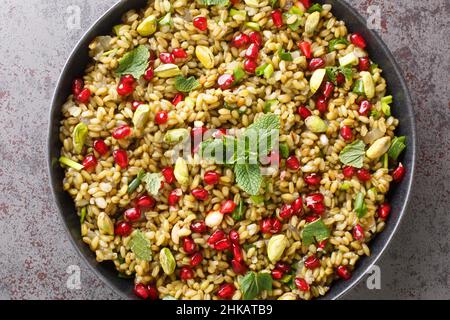 Gesundes veganes Essen aus Freeh mit Granatapfel, Nüssen und Kräutern aus der Nähe in einem Teller auf dem Tisch. Horizontale Draufsicht von oben Stockfoto
