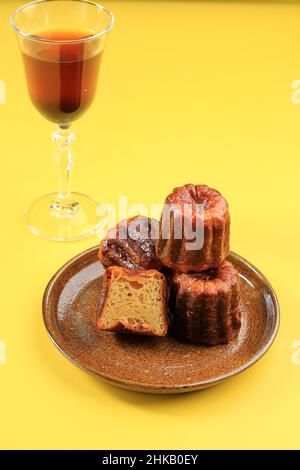 Caneles de Bordeaux – Traditionelles französisches Süßes Dessert auf Keramikplatte, gelber Hintergrund. Stockfoto