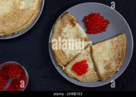 Blini Dreiecke oder Crepes mit rotem Kaviar auf Platte mit Jar Stockfoto