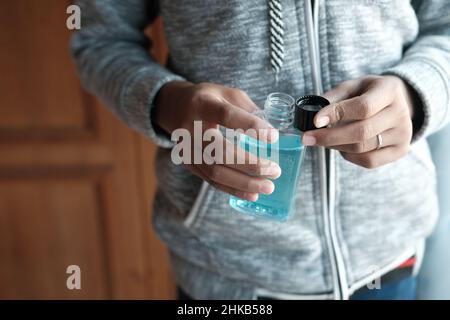 Halten Sie einen Mundspülbehälter mit der Hand auf blauen Hintergrund Stockfoto