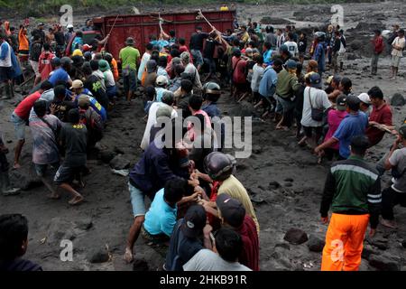 Yogyakarta, Indonesien. 3rd. Februar 2022. Menschen versuchen, Fahrzeuge, die in Materialien aus kalter Lava vom Berg Merapi am Boyong River im Bezirk Sleman, Yogyakarta, Indonesien, gefangen sind, zu evakuieren, 3. Februar 2022. Starke Regenfälle um den Hang des Mount Merapi am Donnerstag verursachten einen Erdrutsch der vulkanischen Lagerstätte am Boyong River. Es wurden keine Verletzten gemeldet. Quelle: Priyo Utomo/Xinhua/Alamy Live News Stockfoto