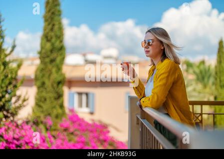 Frau mit Rotwein genießt ihren Urlaub auf dem Balkon. Stockfoto