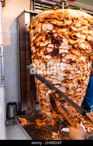 Koch schneidet gegrilltes Hühnerfleisch aus rotierendem Spieß und macht traditionellen türkischen Street Food Döner Kebab (Shawarma oder Gyros in anderen Kulturen) in Istan Stockfoto