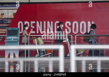 Badung, Bali, Indonesien. 3rd. Februar 2022. Eine Gruppe von Reisenden aus Japan bringt ihr Gepäck mit und geht über die Texttafel „Opening soon“. Der erste reguläre internationale Flug von Garuda Indonesia Airways, Airbus 330-300 mit der Seriennummer GA 881, vom japanischen Flughafen Narita kommt am Flughafen I Gusti Ngurah Rai, Bali an. Der Flug, der um 9:15 Uhr Ortszeit in Tokio startet und um 16:33 Uhr in Bali eintrifft, umfasst Menschen aus der Reisebranche, die aus 6 japanischen Bürgern und 6 indonesischen Bürgern bestehen, die in Japan leben. Dieser Flug gilt als der erste internationale Flug, der nach B kommt Stockfoto