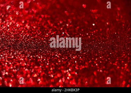Rote Herzen, glitzernder Bokeh-Hintergrund, abstrakte, defokussierte Textur des Valentinstag Stockfoto