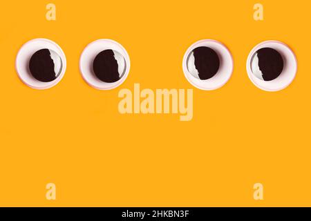 Ein Paar schöne Augen auf einem orangefarbenen Hintergrund mit Kopierfläche Stockfoto