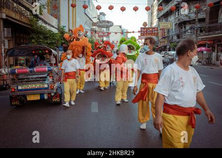 Eine Gruppe von Löwentänzern geht eine Straße neben einem Tuktuk entlang.das Mondneujahr in Bangkok ist in diesem Jahr eine feierliche Angelegenheit als in den Vorjahren. Die Regierung hatte große Feiern technisch abgesagt, aber in Chinatown verlangsamte eine Gruppe von Löwentänzern den entgegenkommenden Verkehr auf der Yaowrat-Straße. In einer Seitenstraße am Wat Lokanukroh war die einzige Aufregung für den Tag der Ausbruch eines kleinen Feuers, der verursacht wurde, als große brennende rote Kerzen aufeinander einstürzten; Wächter eilten für einen Feuerlöscher. Viele Thais chinesischer Abstammung führten weiterhin ungestört Riten und Gebete am Schrein durch. (P Stockfoto