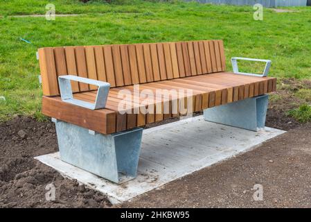 Neue, moderne Parkbank aus Holz und Aluminium, die um das Alexander Stadium in Perry Barr, Birmingham herum installiert wurde und für die Commonwealth Games 2022 bereit ist Stockfoto