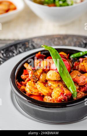 Garnelen-Eintopf mit Tomaten, Knoblauch und Paprika in einer Schüssel mit schwarzem Stein Stockfoto