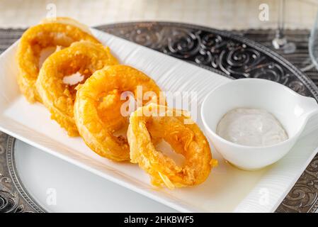 Köstliche Calamari auf einem weißen Porzellanteller mit Salat und Sauce Stockfoto