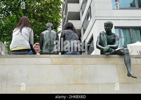 Gruppe von Bronzefiguren und Touristen an der Uferpromenade der Spree in Berlin. Stockfoto