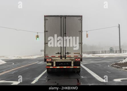 Rückansicht eines Sattelaufliegers auf der Straße an einem nebligen Wintertag Stockfoto