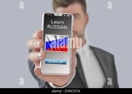 Online-Konzept Russisch lernen mit einer Person zeigen E-Learning-App auf dem Handy mit der Flagge von Russland isoliert Stockfoto