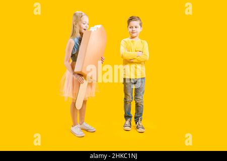 Der Bruder ist nicht glücklich, dass die Schwester die Süßigkeit nicht teilt. Ein riesiges köstliches, appetitliches Dessert. Ein Mädchen hält ein großes Eis auf einem Stock Stockfoto