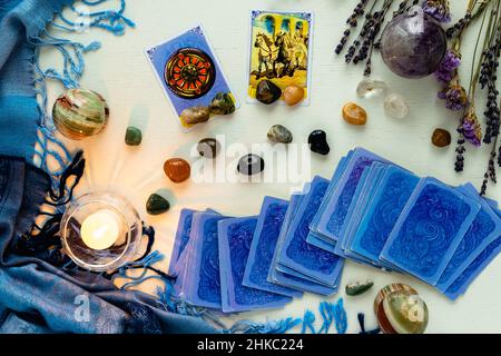 Minsk, Weißrussland - 2022. Februar: Glück- und Wagenkarten in Tarot-Weissagung mit Kerzen und Steinen auf einem hellen Tisch mit getrockneten Blumen und einem blauen t Stockfoto