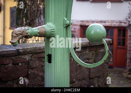 Alt dekorierte manuelle Wasserpumpe aus grün lackiertem Gusseisen auf einem öffentlichen Platz in einer kleinen Altstadt in süddeutschland Stockfoto