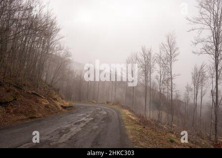 Bergstraße/Pass in Italien mit einigen geflickten Löchern auf der Straße und nebeligem Wetter. Stockfoto