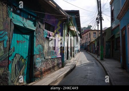 Valparaiso, Chile - Februar 2020: Enge, leere Straße in Valparaiso mit Graffiti bemalten Gebäuden. Street Art in Valparaiso Stockfoto