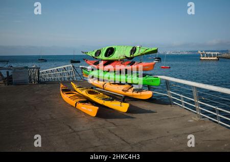 Valparaiso, Chile - Februar 2020: Mehrere bunte Kajaks auf dem Muelle Baron Pier in der Bucht von Bahia de Valparaiso im Pazifischen Ozean gestapelt. Stockfoto