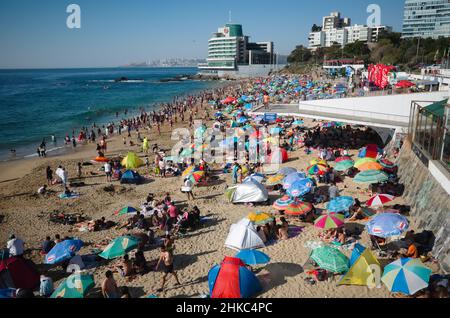 Vina del Mar, Valparaiso, Chile - Februar 2020: Menschenmenge mit Sonnenschirmen, die sich an sonnigen Tagen am Strand von Playa Caleta Abarca entspannen und sonnen Stockfoto