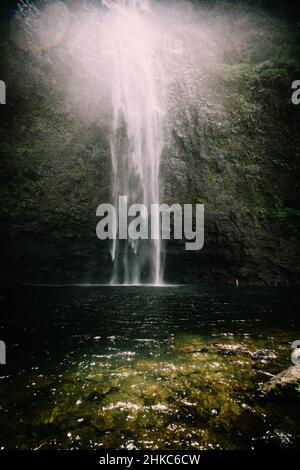 Die Hanakapi'ai Wasserfälle fließen über massiven Felsen in einen klaren Pool Stockfoto