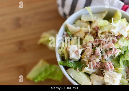 Eine Nahaufnahme eines Caeser Salats mit Huhn und Speck in einer weißen Schüssel. Stockfoto