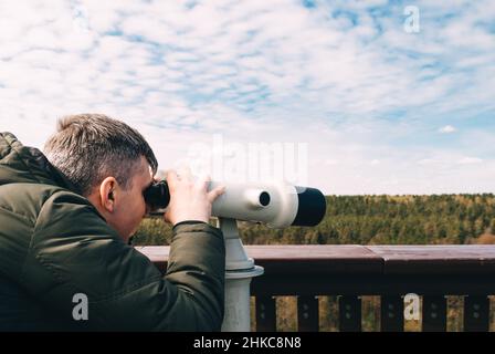 Der Mann schaut mit dem Tower Viewer in die Entfernung von der Aussichtsplattform Stockfoto