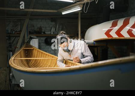 Kanubauer schleift das Boot in einer kleinen Werkstatt Stockfoto