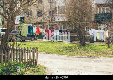 Die Wäsche wird im alten Frühlingshof mit einem Zaun und Autos getrocknet Stockfoto