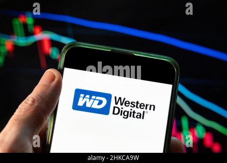 In dieser Abbildung ist das Logo des amerikanischen Computerfestplatten- und Datenspeicherherstellers Western Digital (WD) zu sehen, das auf einem Smartphone mit einem Index der wirtschaftlichen Börse im Hintergrund angezeigt wird. Stockfoto